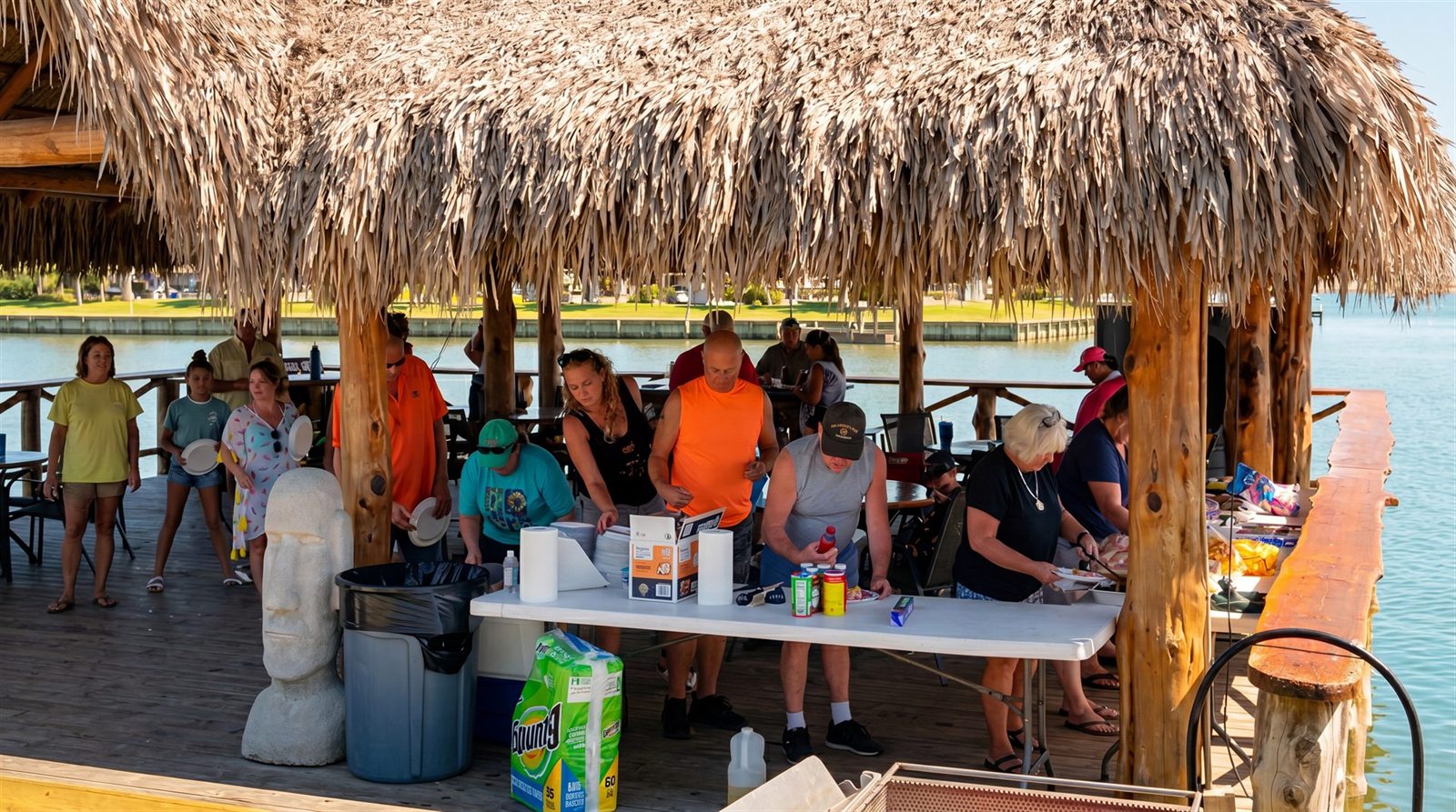 Resort Guests Gathering for Community BBQ Feast Under Thatched Palapa